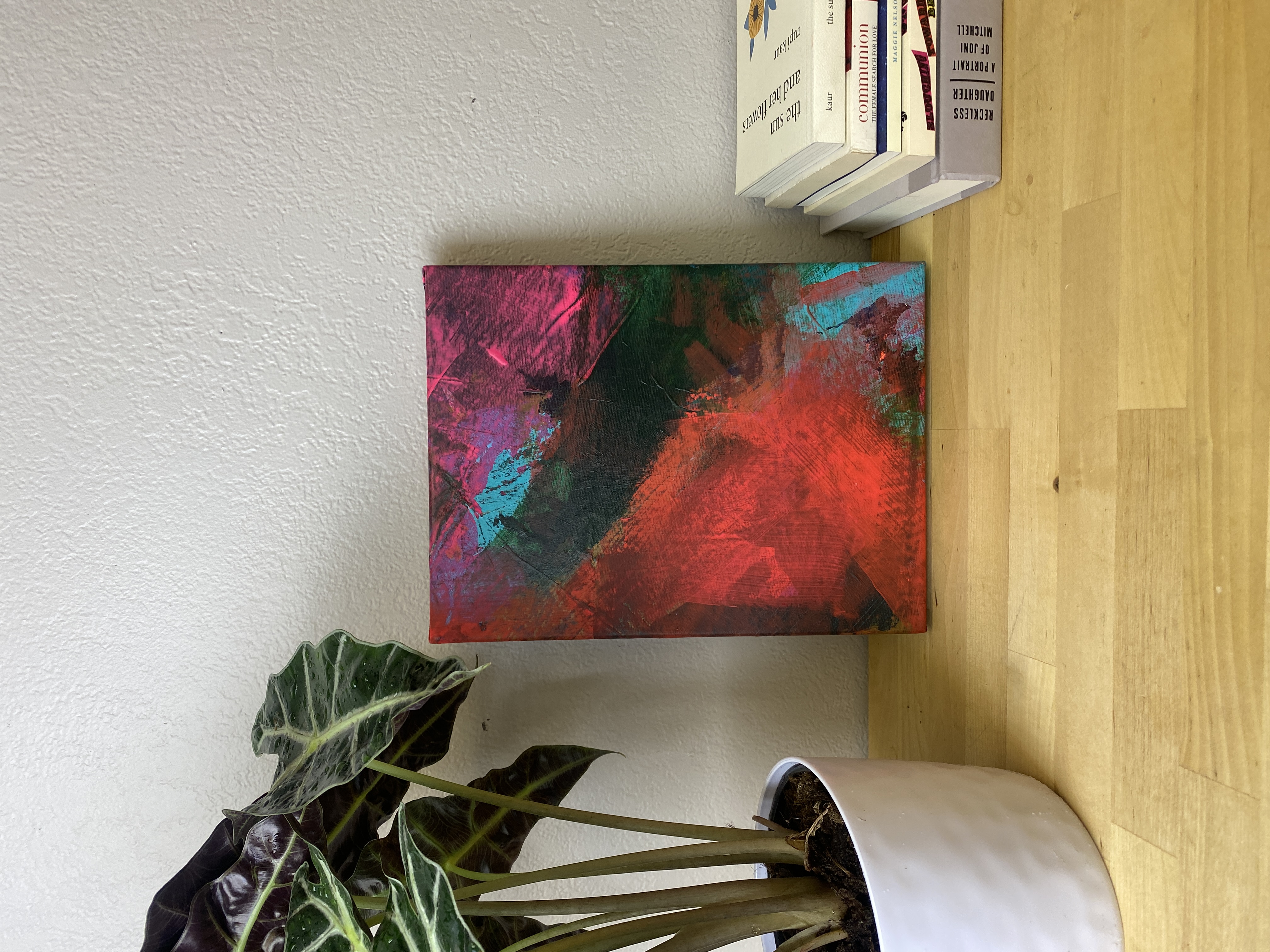 Small abstract canvas — red and teal displayed on shelf with books