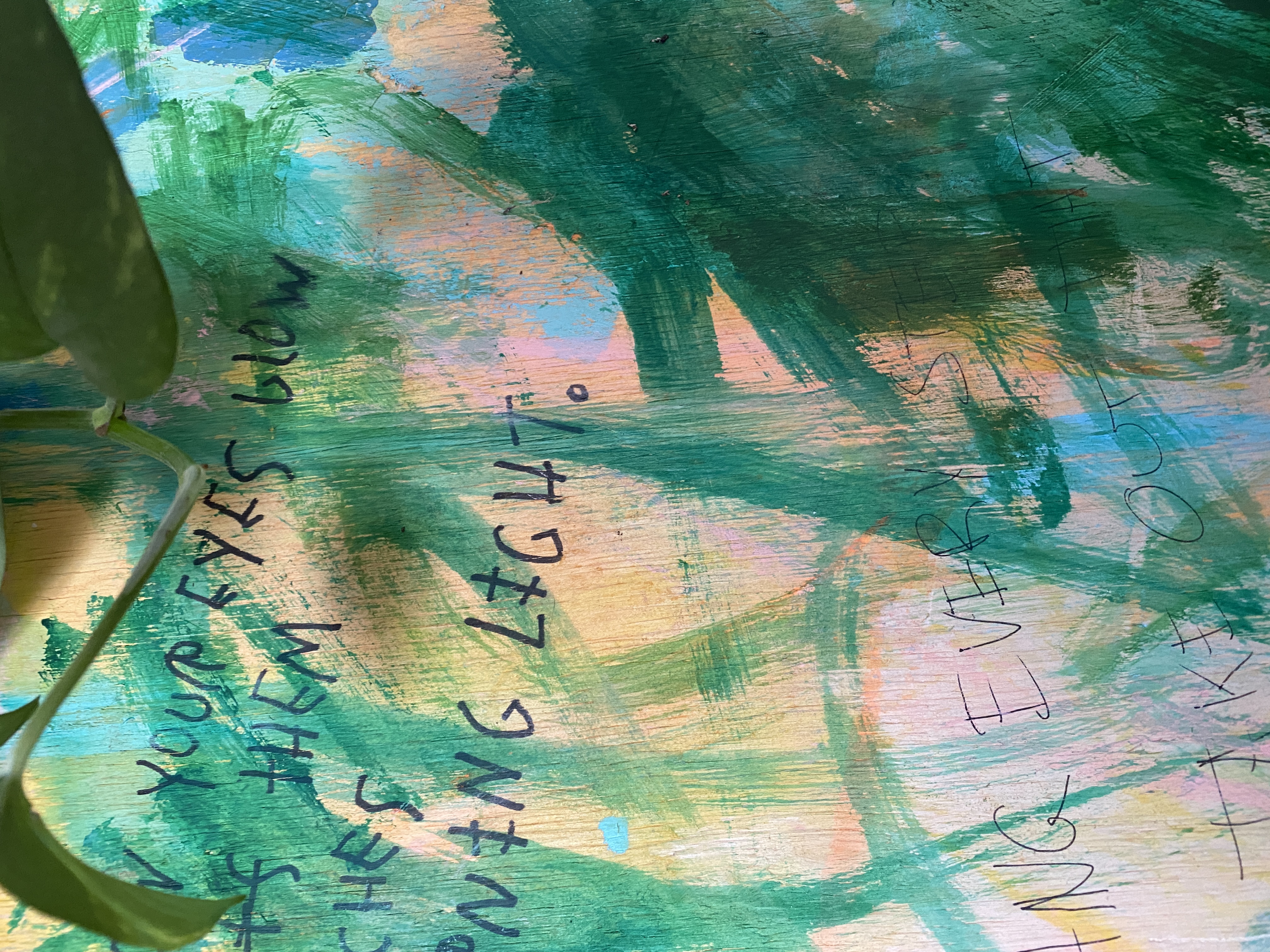 Close-up of canvas showing handwritten poetry visible beneath washes of green and teal paint