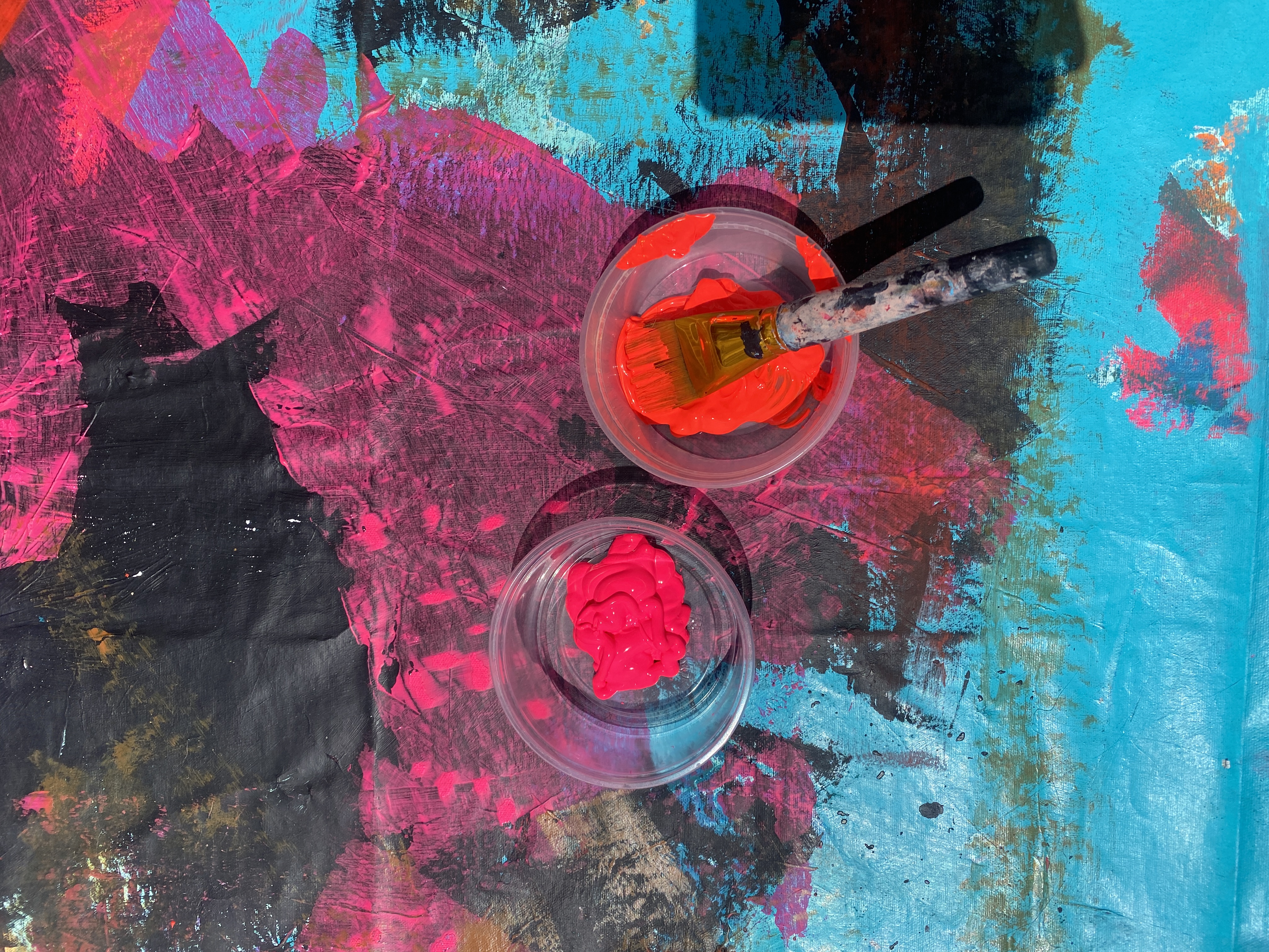 Paint cups and palette knife on wet canvas